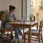 Eine Person arbeitet am Laptop in einer Ferienwohnung mit Blick in einen mediterranen Innenhof.